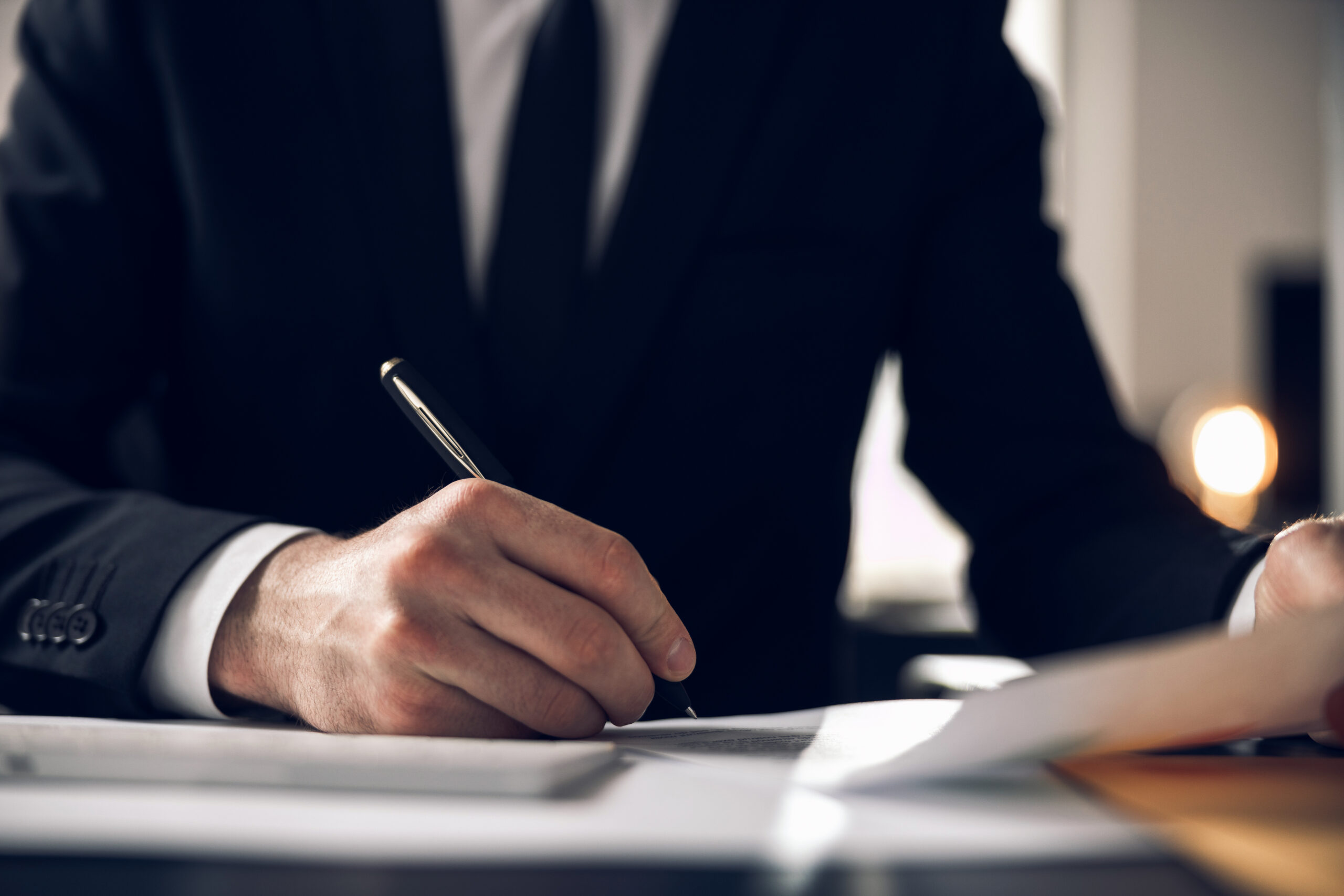 Cropped photo of man signing paper in office