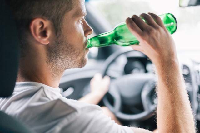 Fahrer trinkt aus grüner Flasche am Steuer – Alkohol am Steuer