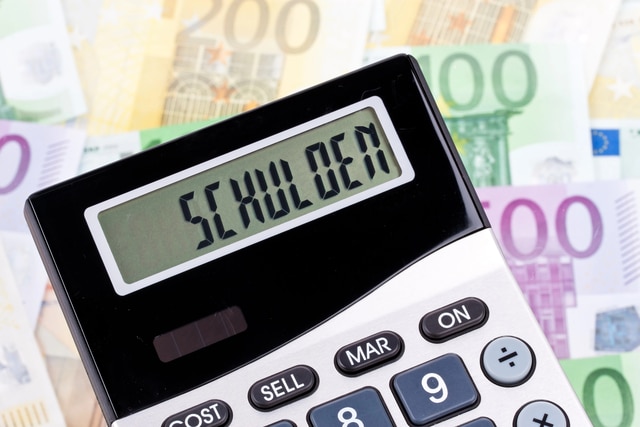 Taschenrechner mit Anzeige „Schulden“ vor Euro-Scheinen – fällige Forderungen