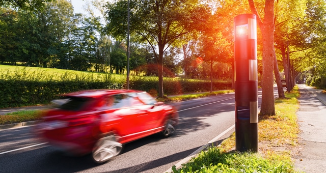 Stationärer Blitzer erfasst ein rotes, schnelles Auto – Geschwindigkeitsüberschreitung