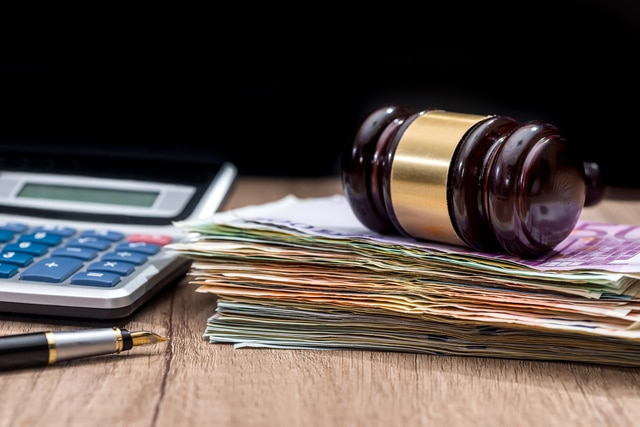 Richterhammer auf Geldscheinen neben Taschenrechner