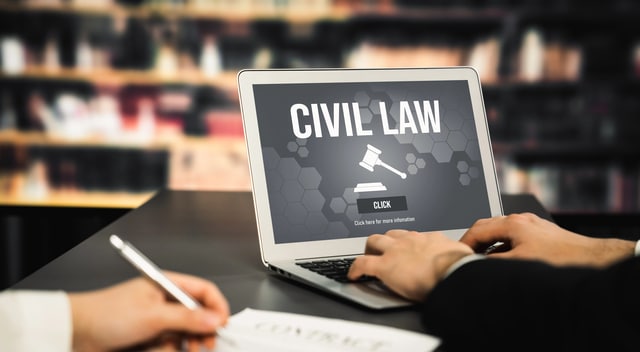 Laptop mit „Civil Law“-Bildschirm, Hände arbeiten an einem Vertrag